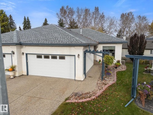 Attached multi-car garage with overhead doors and transom-style windows - 7 Linkside Pl, Spruce Grove, AB 