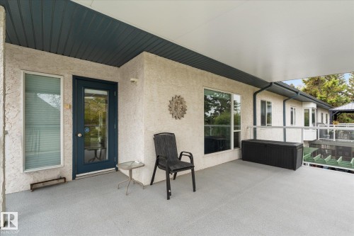 Spacious covered patio with textured exterior walls, a full-lite entry door, and a horizontal window - 7 Linkside Pl, Spruce Grove, AB 