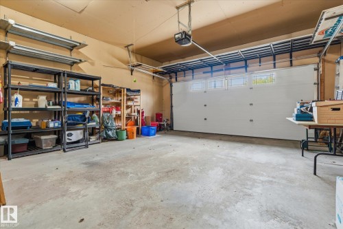 Concrete flooring with perimeter shelving and a white garage door featuring upper windows - 7 Linkside Pl, Spruce Grove, AB 