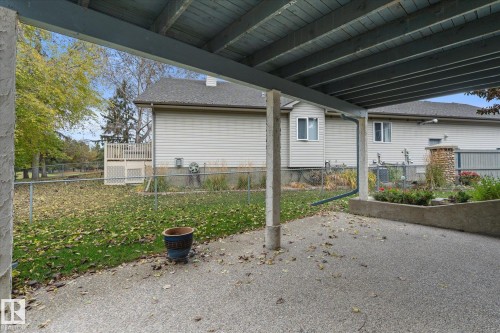 Covered concrete patio with concrete support columns, a built-in planter, and a chain-link fence - 7 Linkside Pl, Spruce Grove, AB 