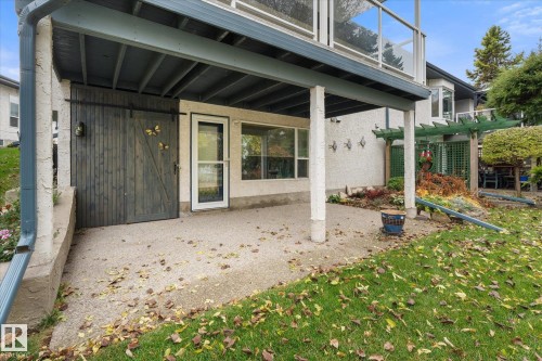 Covered patio with an exposed aggregate finish, featuring a sliding barn door and an exterior entry door - 7 Linkside Pl, Spruce Grove, AB 