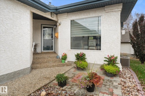 Stucco exterior featuring a covered entry, an exposed aggregate walkway, a paver stone patio, and a large window - 7 Linkside Pl, Spruce Grove, AB 