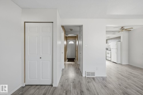 Light wood-finish flooring, white walls, white bifold closet door, ceiling fan with light kit, white appliances - 164 Dickinsfield Court Nw, Edmonton, AB 
