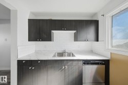 Dark wood-finish cabinetry with silver hardware, white subway tile backsplash, white marble-look countertop, and a stainless steel double-basin sink - 