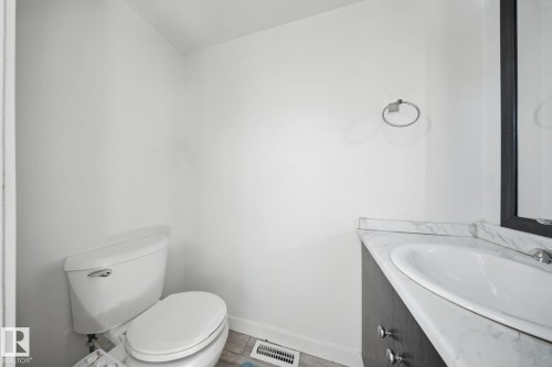 White toilet and a vanity with a white countertop, featuring an undermount sink - 164 Dickinsfield Court Nw, Edmonton, AB 