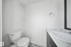 White toilet and a vanity with a white countertop, featuring an undermount sink - 