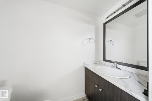 Dark wood-finish vanity with chrome hardware, an integrated basin, and a light-toned countertop - 164 Dickinsfield Court Nw, Edmonton, AB 