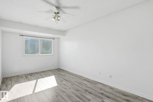Recessed window with horizontal blinds, overhead ceiling fan with light fixture, light wood-finish flooring, and white painted walls - 164 Dickinsfield Court Nw, Edmonton, AB 