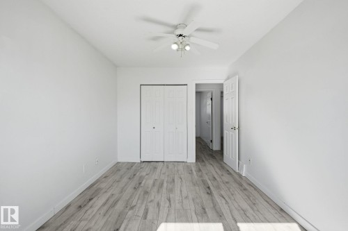 Room featuring wood-finish flooring, white walls, a ceiling fan with integrated lighting, and a bi-fold closet door - 164 Dickinsfield Court Nw, Edmonton, AB 