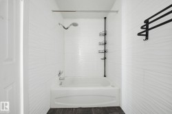 White subway tile surround with textured accent, integrated bathtub, and dark wood-finish flooring - 