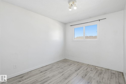 Window with a black curtain rod, wood-finish flooring, and a ceiling-mounted light fixture - 164 Dickinsfield Court Nw, Edmonton, AB 