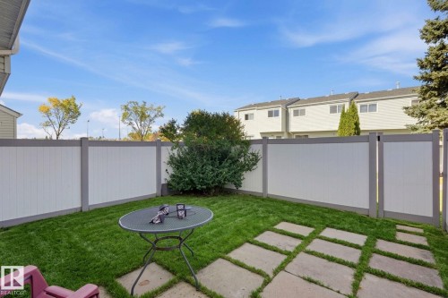 Fenced backyard featuring a manicured lawn, concrete paver patio, and mature shrubbery - 164 Dickinsfield Court Nw, Edmonton, AB 