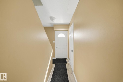 Entryway featuring a white door with an arched window insert, wood-finish flooring, and light-toned wall paint - 164 Dickinsfield Court Nw, Edmonton, AB 