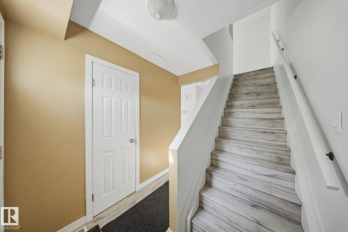 Staircase featuring wood-finish treads and a white handrail - 164 Dickinsfield Court Nw, Edmonton, AB 