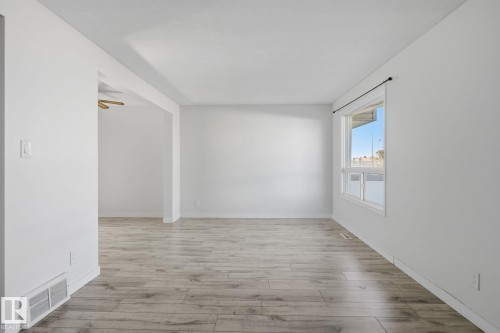 Spacious room featuring wood-finish flooring and white walls - 164 Dickinsfield Court Nw, Edmonton, AB 