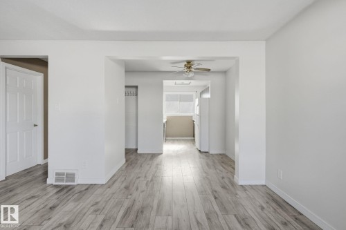 Updated wood-finish flooring throughout, bright white walls, a ceiling fan fixture, and a kitchen with white appliances - 164 Dickinsfield Court Nw, Edmonton, AB 
