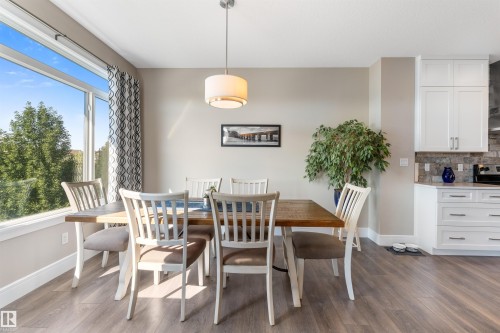 Expansive window with roller blinds, wood-finish flooring, recessed lighting, and white cabinetry with stone backsplash - 3334 Parker Loop Sw, Edmonton, AB 