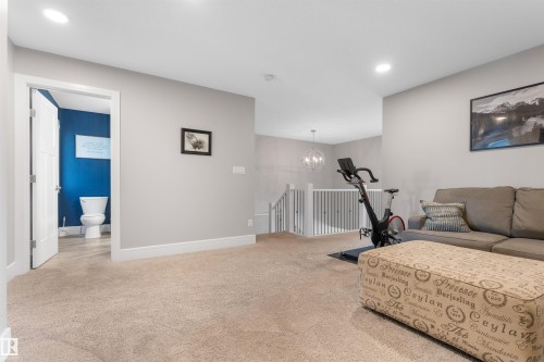 Carpeted open area with recessed lighting, white trim, and a built-in staircase - 3334 Parker Loop Sw, Edmonton, AB 