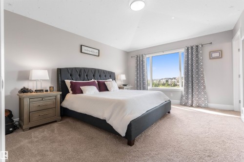 Vaulted ceiling with flush-mount lighting, large window with ample natural light, neutral wall color, and plush carpeting - 3334 Parker Loop Sw, Edmonton, AB 