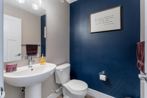 Pedestal sink with chrome faucet, wall-mounted mirror, and vanity lighting - 3334 Parker Loop Sw, Edmonton, AB 