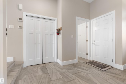 Entryway featuring light-toned walls, tile flooring, white panel doors, and a built-in closet - 3334 Parker Loop Sw, Edmonton, AB 