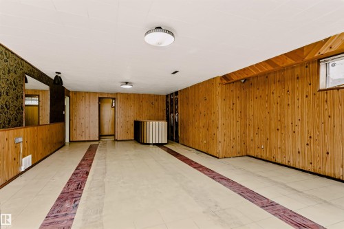 Spacious room featuring wood paneling, a built-in bar, recessed lighting, and tile flooring with a central accent - 11440 44A Avenue Nw, Edmonton, AB 