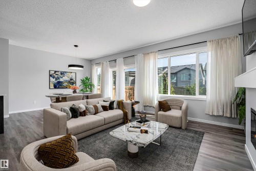 Expansive living area with wood-finish flooring, large windows, and a built-in fireplace - 9227 223 Street Nw, Edmonton, AB 