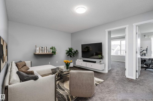 Light gray wall paint, textured carpeting, recessed lighting, white trim, and a wall-mounted floating media console - 9227 223 Street Nw, Edmonton, AB 