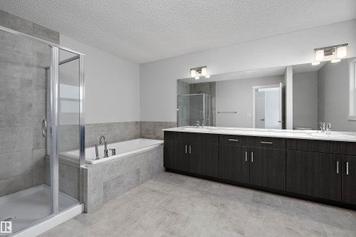 Glass-enclosed shower, built-in soaking tub, dual vanity with undermount sinks, wood-finish cabinetry, and large mirror - 9227 223 Street Nw, Edmonton, AB 