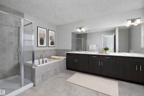 Tiled walk-in shower with glass enclosure, separate soaking tub, expansive dual vanity with integrated sinks, full-width mirror, and overhead vanity lighting - 9227 223 Street Nw, Edmonton, AB 