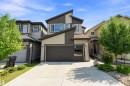 Contemporary exterior with a multi-textured facade, angular roofline, two-car garage with frosted glass panels, concrete driveway, and mature landscaping - 9227 223 Street Nw, Edmonton, AB 