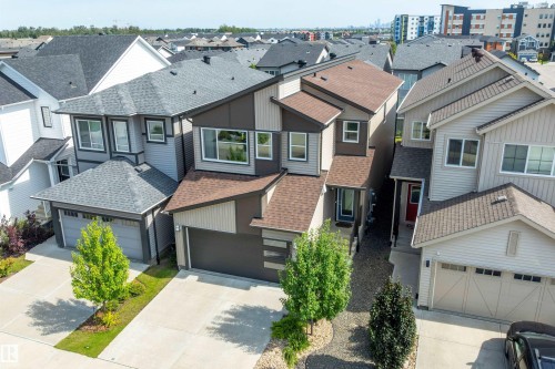 Modern architectural style featuring a multi-tone exterior, attached garage, paved driveway, and mature landscaping - 9227 223 Street Nw, Edmonton, AB 