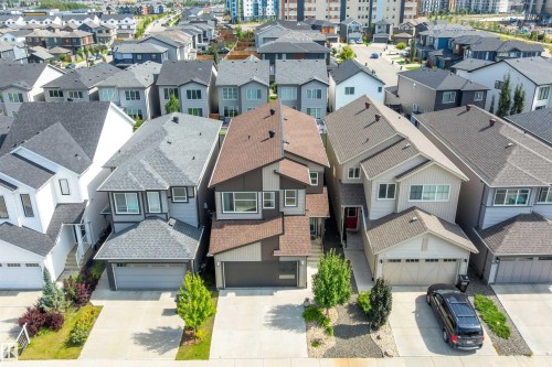 Contemporary residential architecture featuring a brown and gray exterior, attached garage, and landscaped front yard - 9227 223 Street Nw, Edmonton, AB 