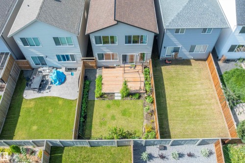 Rear exterior with multiple windows and a sliding glass door, a wooden deck, and a fenced yard with established landscaping - 9227 223 Street Nw, Edmonton, AB 