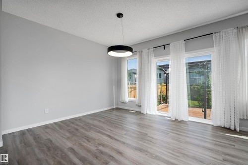 Wood-finish flooring, contemporary pendant light fixture, and multiple windows with sliding door access to outdoor space - 9227 223 Street Nw, Edmonton, AB 