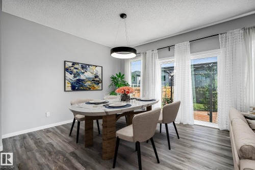 Wood-finish flooring, contemporary circular pendant light fixture, light gray wall tones, and sliding glass doors - 9227 223 Street Nw, Edmonton, AB 