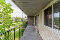 Private balcony with textured stucco exterior, sliding patio door, and white frame windows - 