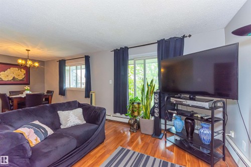 Wood-finish flooring, recessed lighting, and a modern chandelier illuminate the living and dining areas - #6 3819 76 St Nw, Edmonton, AB 