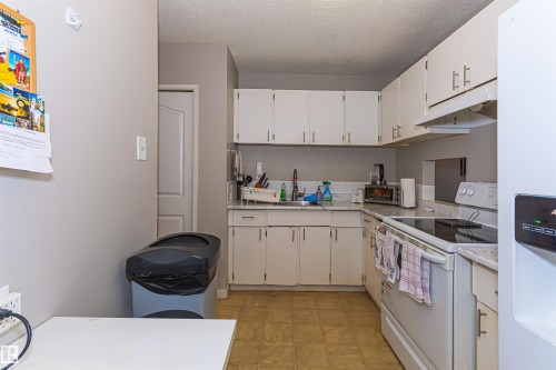 Kitchen with white cabinetry, light countertops, and vinyl flooring - #6 3819 76 St Nw, Edmonton, AB 