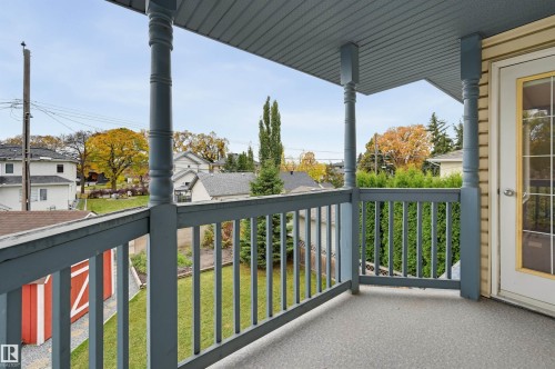 Exterior balcony with painted wood railing, painted wood columns, and a textured floor surface - 7521 111 Avenue Nw, Edmonton, AB 