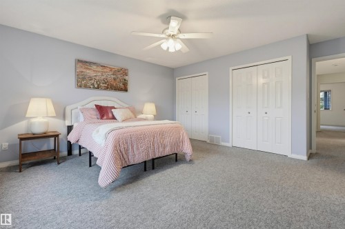Spacious room featuring light-toned walls, carpeted flooring, and multiple bi-fold closet doors - 7521 111 Avenue Nw, Edmonton, AB 