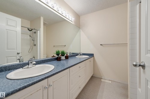 Double vanity with integrated sinks, extended countertop, chrome fixtures, and a large wall-mounted mirror - 7521 111 Avenue Nw, Edmonton, AB 