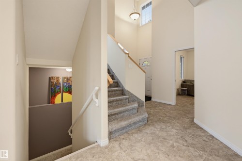 Two-story entry foyer featuring a vaulted ceiling and a staircase with wood railing - 7521 111 Avenue Nw, Edmonton, AB 
