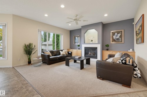 Spacious living area featuring a fireplace with white surround, built-in cabinetry, and large windows - 7521 111 Avenue Nw, Edmonton, AB 