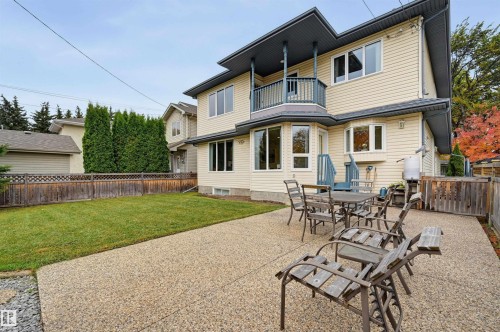 Expansive concrete patio with a manicured lawn, complemented by a wood fence with lattice detailing - 7521 111 Avenue Nw, Edmonton, AB 