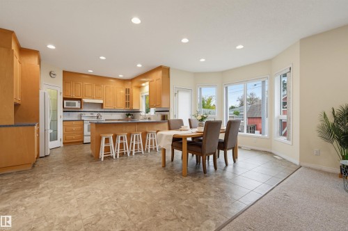 Kitchen featuring wood-finish cabinetry, stainless steel appliances, and an island with bar seating - 7521 111 Avenue Nw, Edmonton, AB 