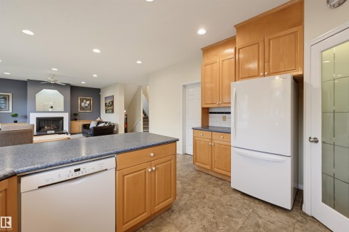 Kitchen island with a dishwasher, wood-finish cabinetry, and solid surface countertops - 7521 111 Avenue Nw, Edmonton, AB 