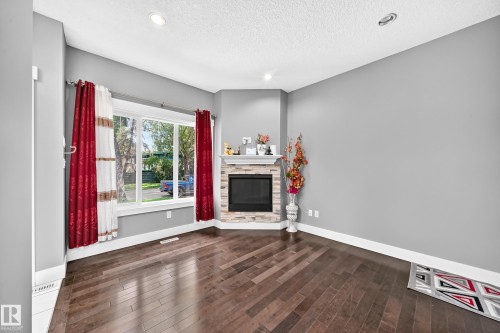 Hardwood flooring, corner fireplace with stone surround and mantel, recessed lighting, and large windows - 12730 118 Street Nw, Edmonton, AB 