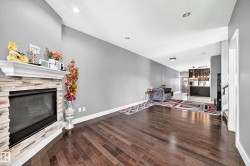 Wood-finish flooring throughout, stone-clad fireplace with mantel, recessed ceiling lighting, and a built-in bar area with pendant lighting - 