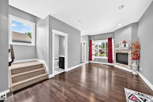 Wood-finish flooring, recessed lighting, and a corner fireplace with a stone surround - 12730 118 Street Nw, Edmonton, AB 
